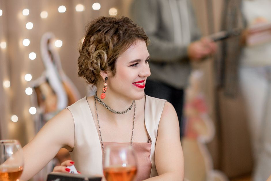 Nasmijana žena uživa na zabavi s pjenušcem i toplim svjetlima